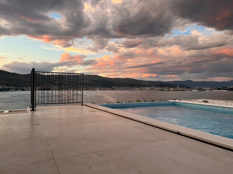 Terrazza con piscina e vista sulla baia con nuvole rosa al tramonto