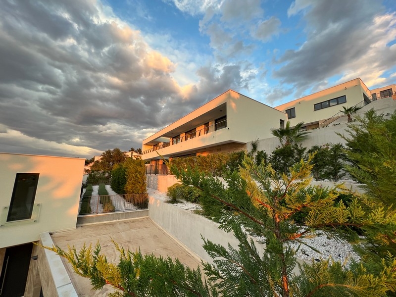 Villa alla luce della sera con cipressi e palme sul pendio