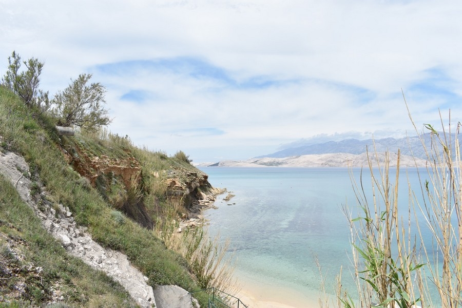 Pendio ripido sopra l'acqua turchese con la spiaggia sotto