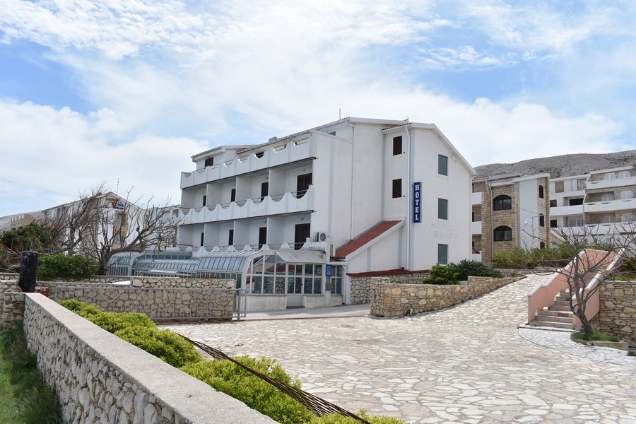 Edificio bianco di un hotel con giardino d'inverno e muro in pietra naturale