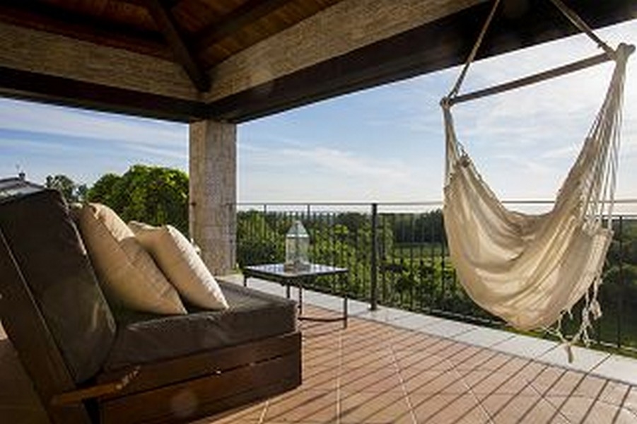 Terrazza coperta con sedia sospesa e divano sopra i campi