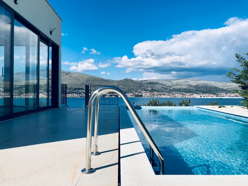 Scaletta della piscina e bordo a sfioro con vista sul paese e sui monti