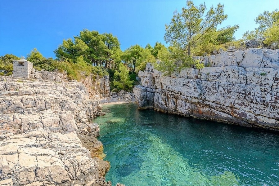 Baia mediterranea con rocce e pini sul mare vicino a Trogir