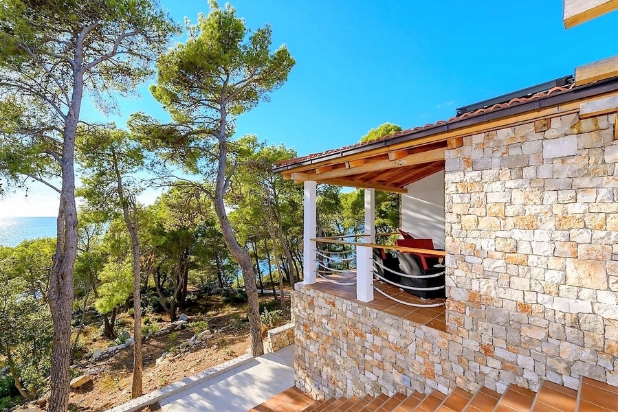 Casa in pietra con terrazza coperta tra i pini sul mare