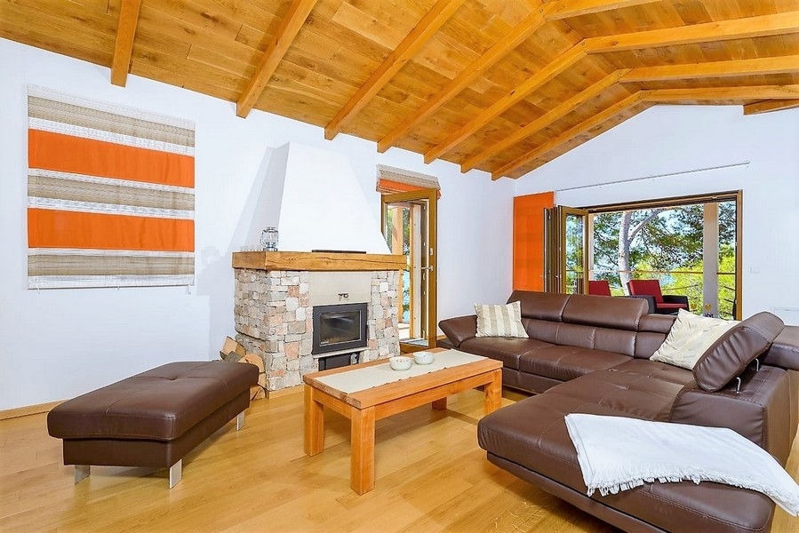 Soggiorno con soffitto a travi di legno e camino in pietra naturale