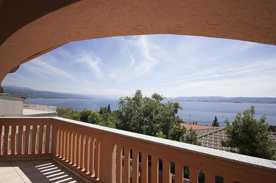 Vista dal balcone ad arco sopra gli alberi fino al mare