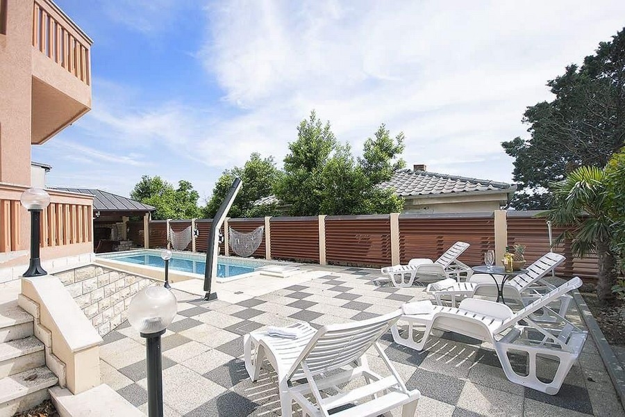 Piscina con lettini sulla terrazza in pietra a scacchi