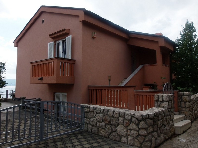 Lato della casa con balcone in legno e terrazza sopra il muro