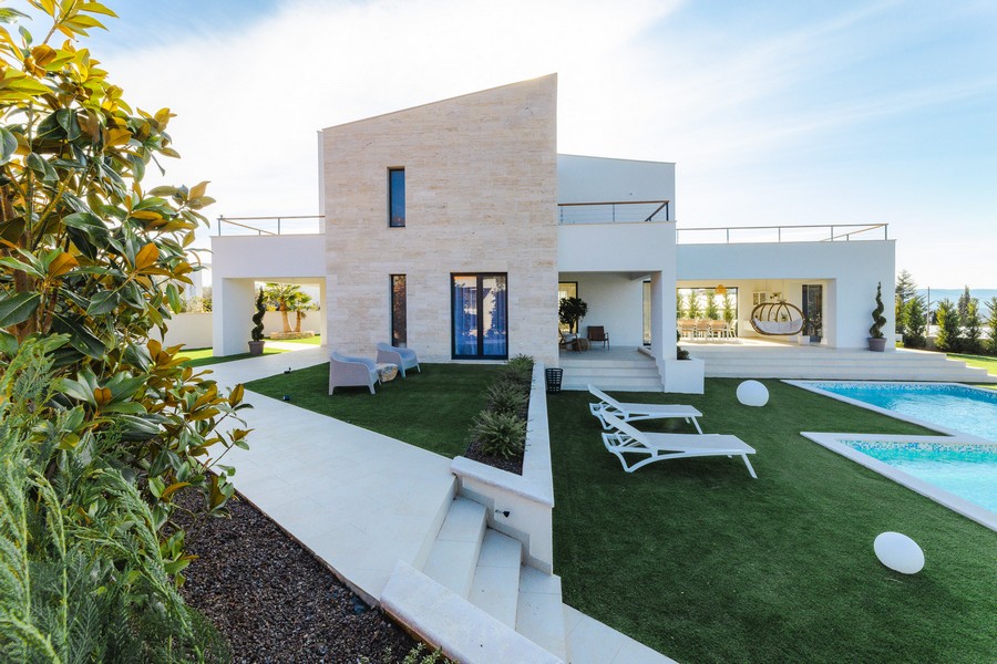 Villa con facciata in pietra naturale e lettini sul prato