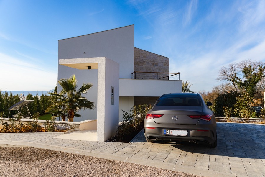 Lato d'ingresso della villa con auto sul vialetto pavimentato