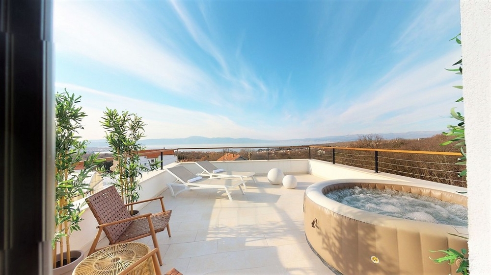 Terrazza sul tetto con vasca idromassaggio e lettini sopra la baia