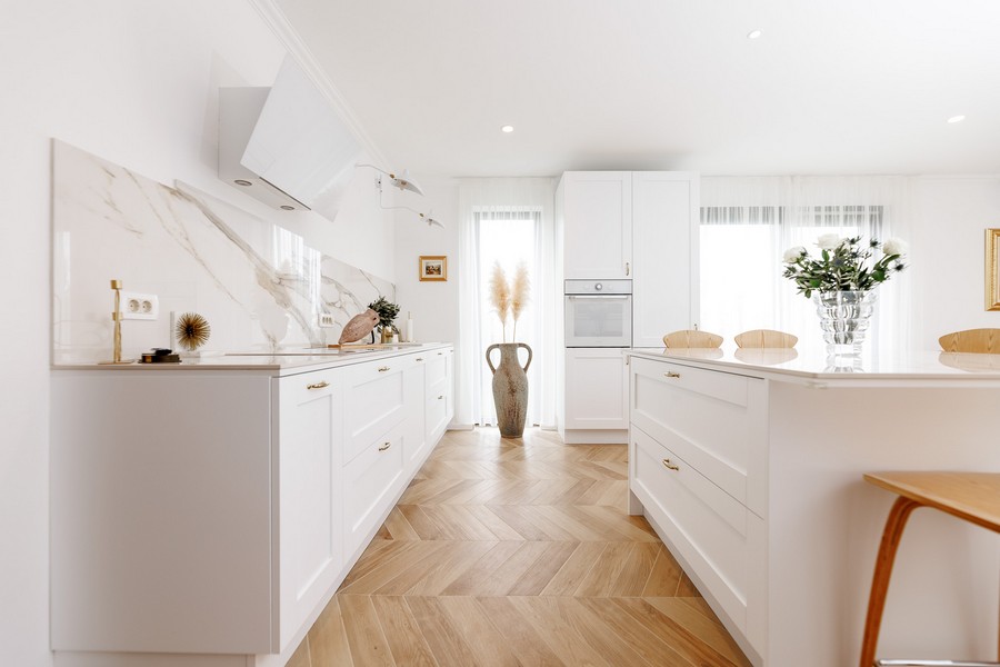 Cucina bianca con rivestimento in marmo e lunga isola cucina