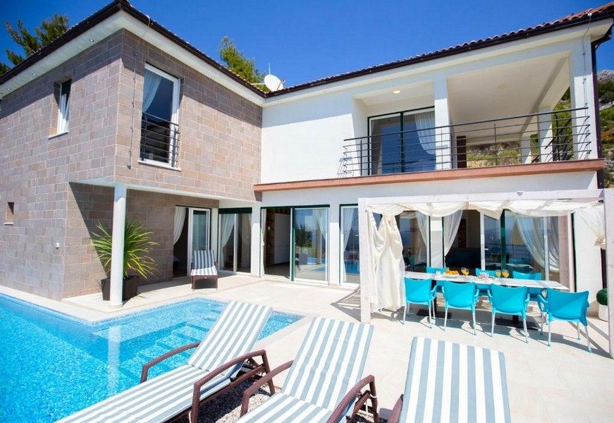 Villa con piscina e padiglione con sedie turchesi