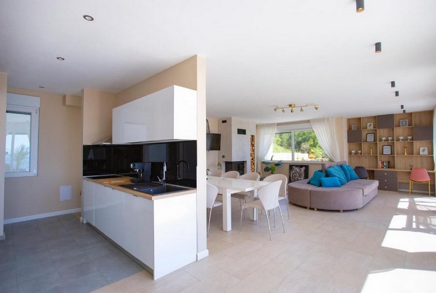 Zona giorno aperta con cucina lineare e tavolo da pranzo bianco