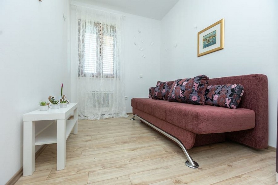 Stanza con divano rosa antico e finestra con tenda di pizzo