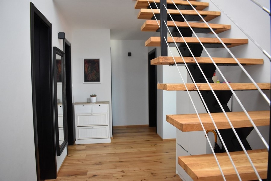 Scala aperta in legno con ringhiera a corda nel corridoio
