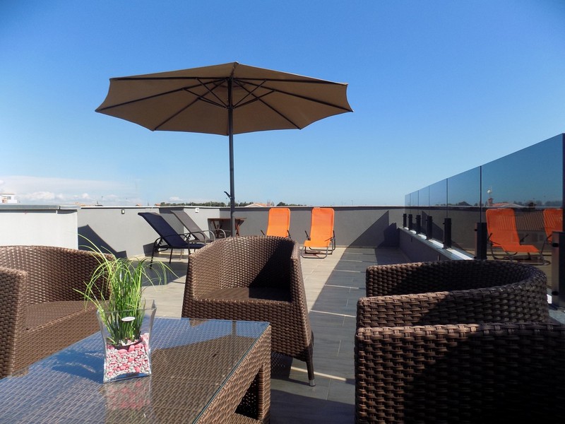 Terrazza sul tetto con ombrellone e mobili in vimini