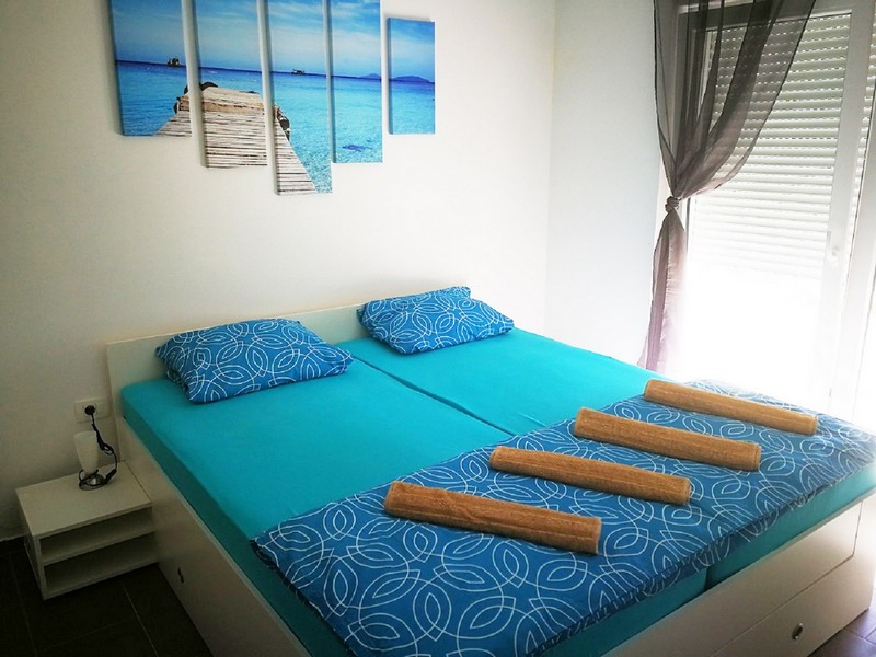 Letto matrimoniale in turchese sotto il quadro con la spiaggia
