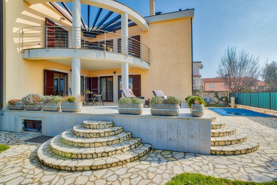 Villa con balcone rotondo e scala in pietra naturale verso la piscina