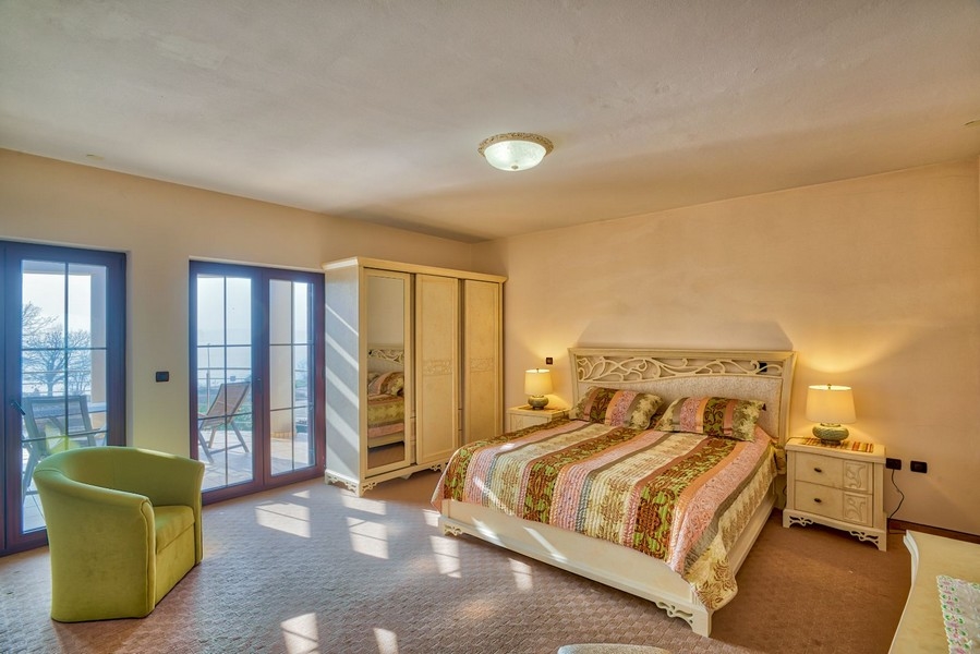 Grande camera da letto con porte del balcone e poltrona verde