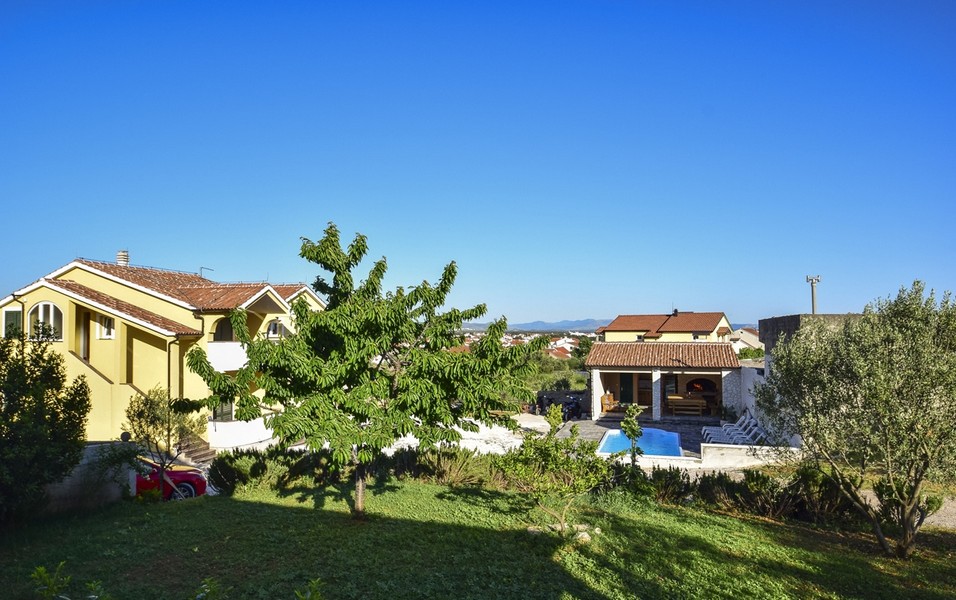 Giardino con albero da frutto e vista su piscina ed edificio annesso