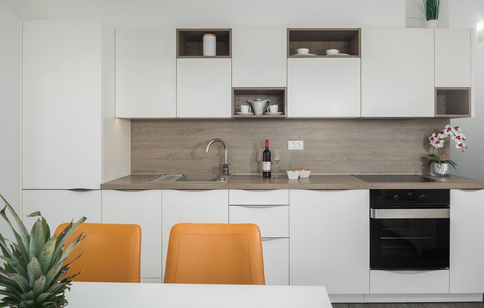 Cucina bianca con parete in legno e sedie arancioni