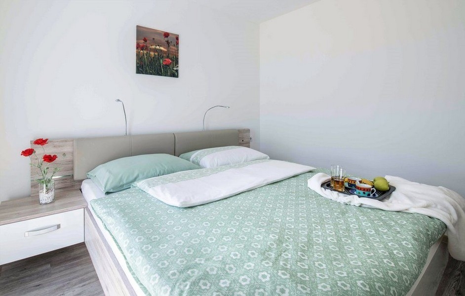 Camera da letto con biancheria verde e quadro con papaveri