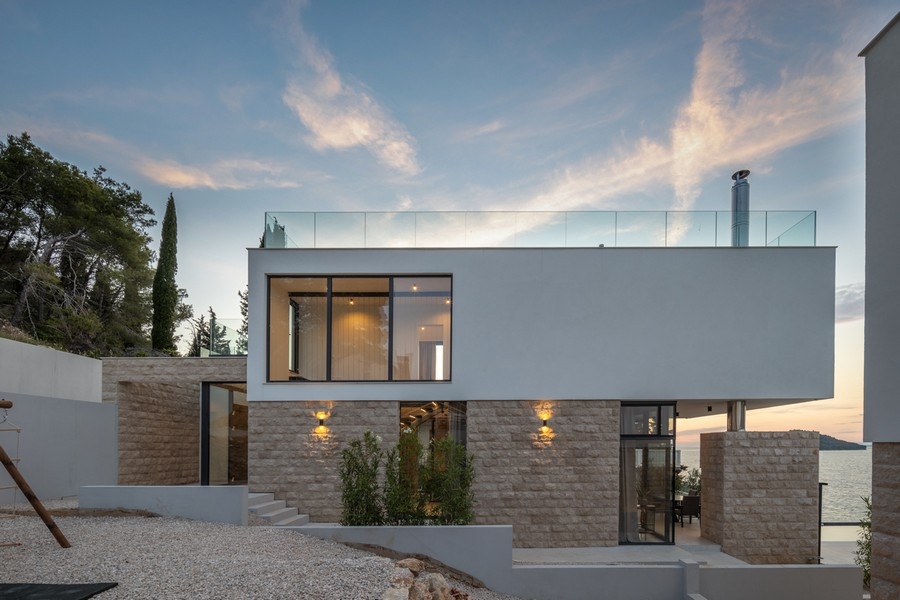 Casa con basamento in pietra naturale alla luce della sera sul mare