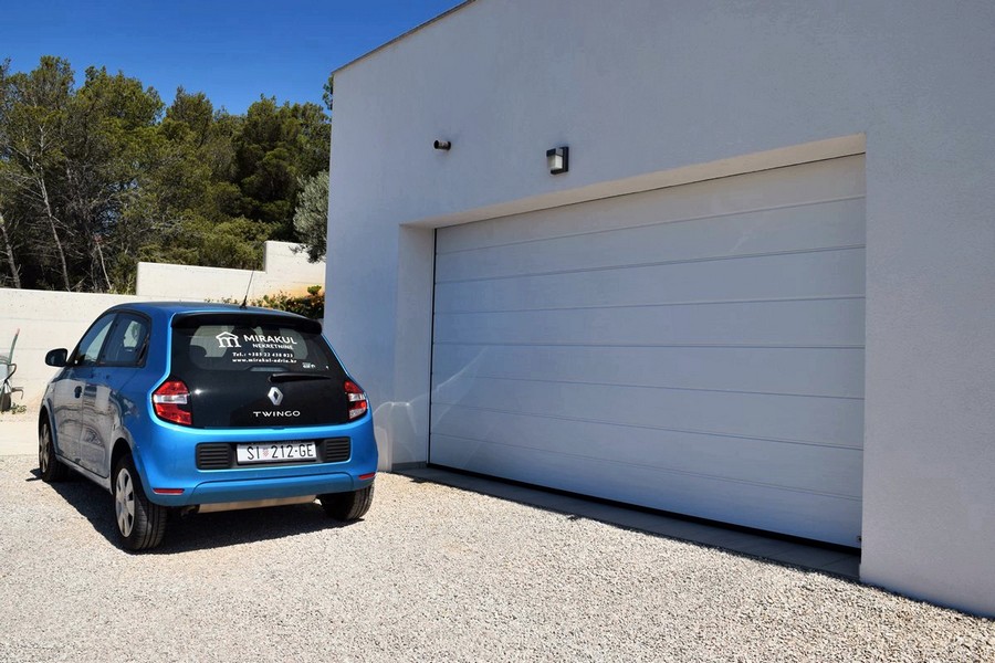 Porta del garage accanto al viale d'accesso in ghiaia