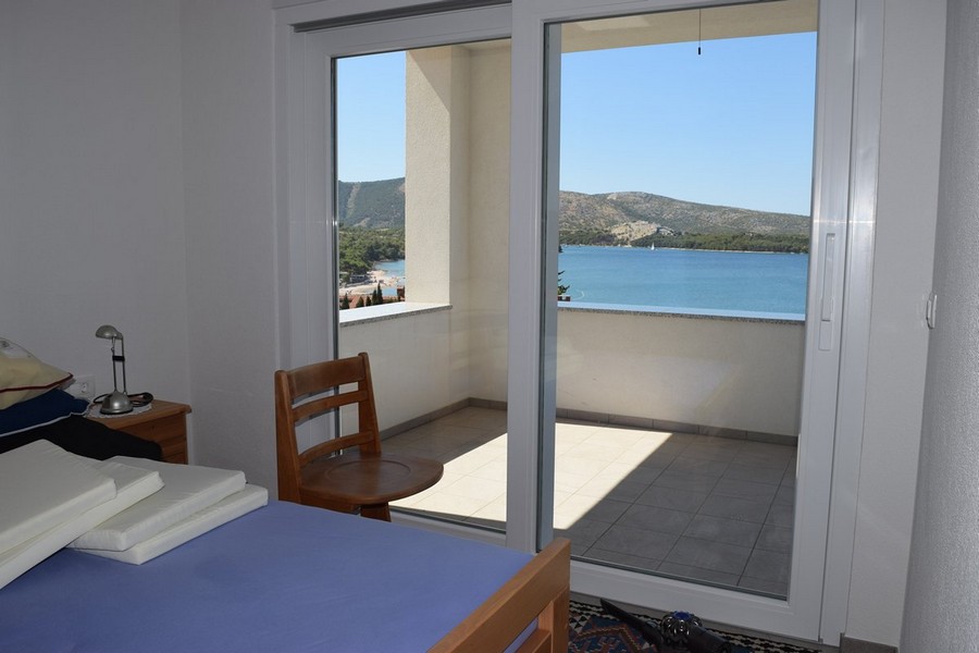 Camera da letto con porta aperta sul balcone sopra la baia