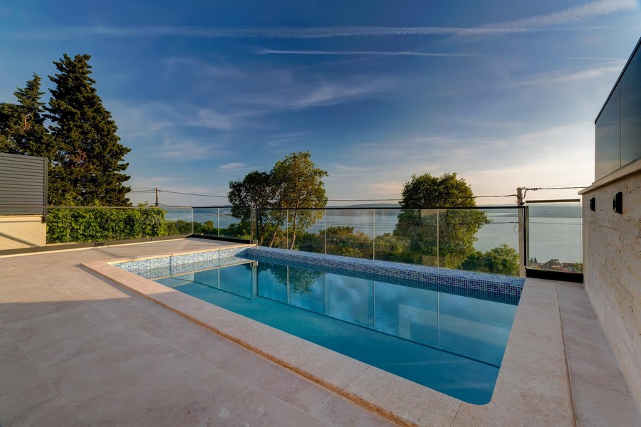 Piscina con parapetto in vetro e ampia vista sulla baia