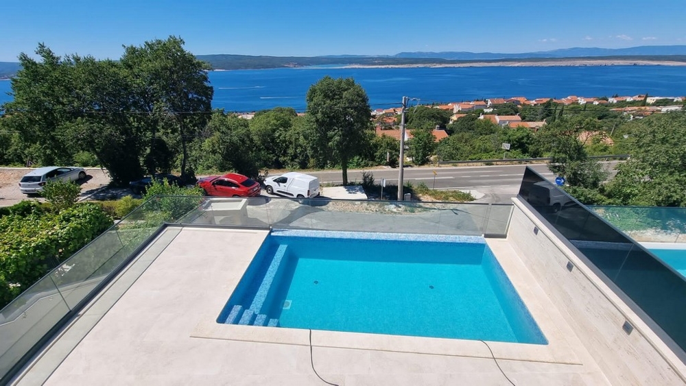 Piscina con ringhiera in vetro e vista oltre la strada sulla baia