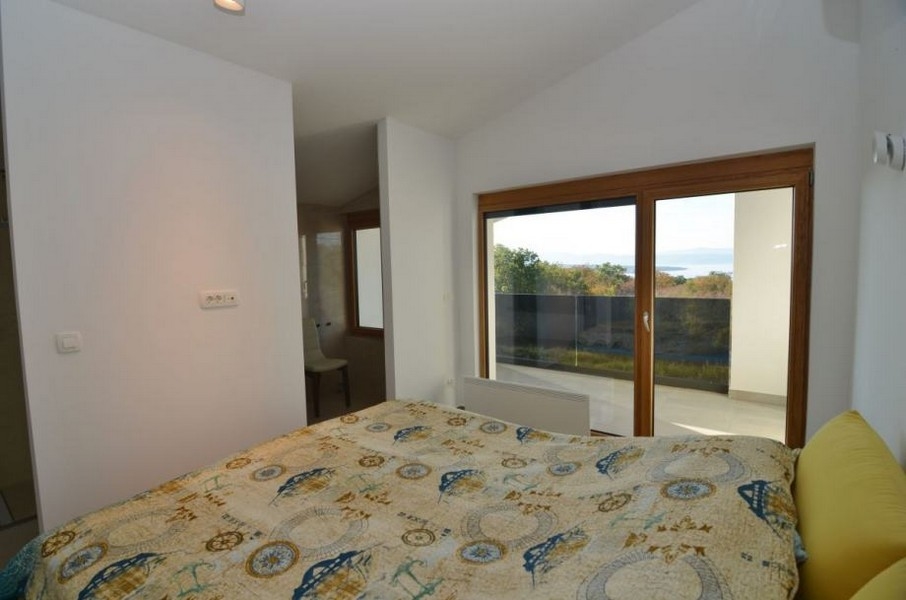 Letto davanti alla vetrata con vista su macchia e mare
