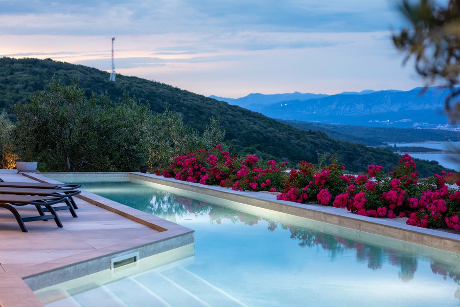 Piscina con lettini e rose rosse sopra la valle