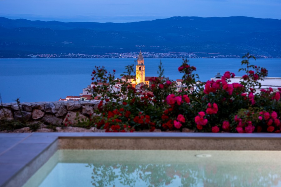 Vista sopra le rose sul campanile illuminato di sera