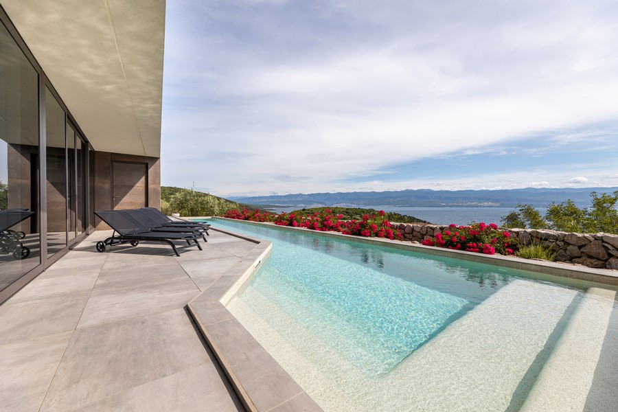 Piscina a sfioro con aiuola di fiori e ampia vista sul mare