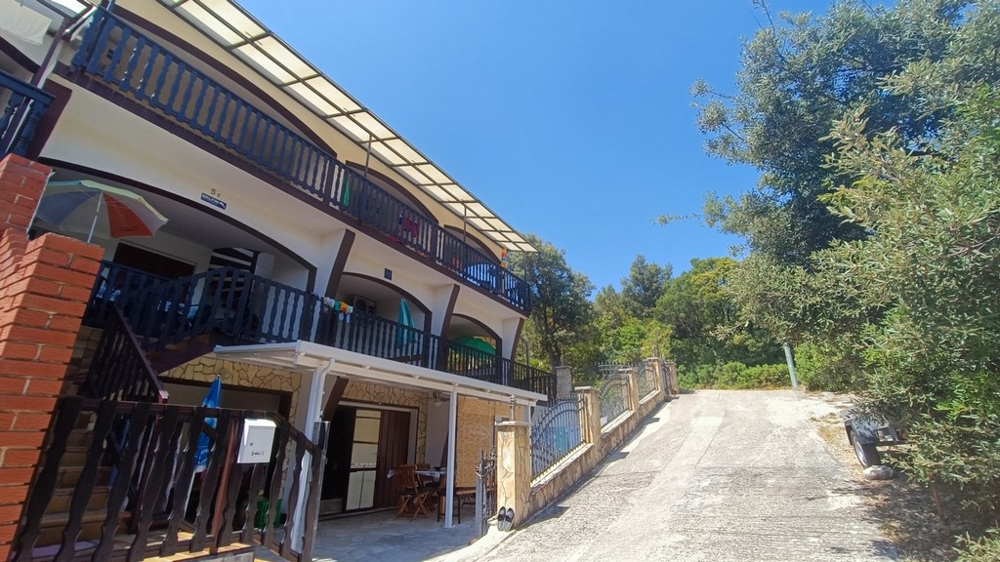 Accesso all'edificio di appartamenti con balconi e vegetazione mediterranea