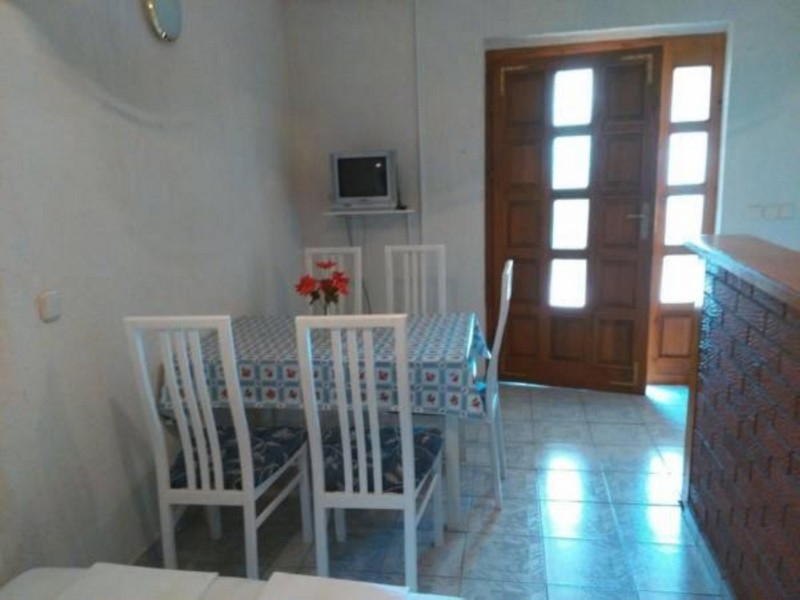 Zona giorno con tavolo, sedie e accesso alla terrazza