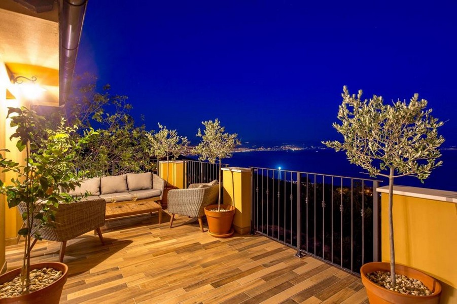 Terrazza in legno con divano in rattan e ulivi alla sera