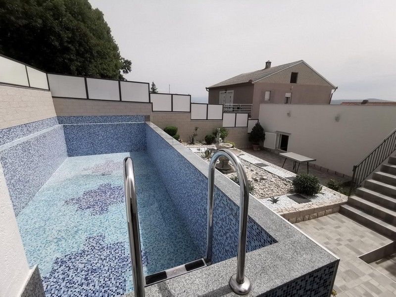 Piscina con mosaico blu e aiuola di ghiaia accanto