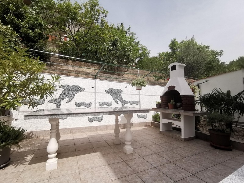 Terrazza con barbecue in muratura e mosaico di delfini alla parete