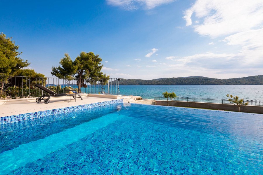 Piscina a sfioro con piastrelle a mosaico direttamente sopra l'acqua