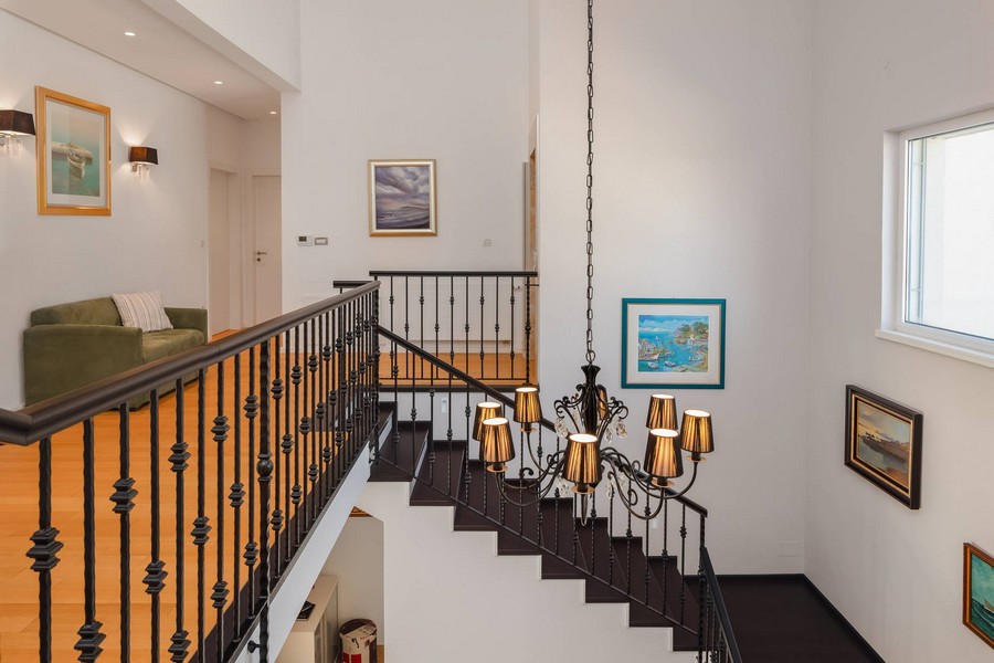 Scala con ringhiera in ferro battuto e grande lampadario
