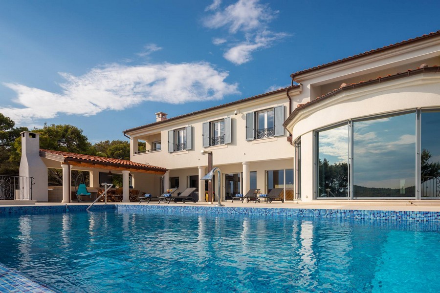 Villa con finestra rotonda e lunga piscina sotto il cielo azzurro