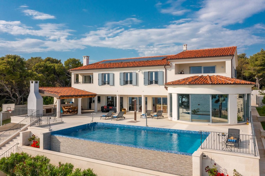 Villa con tetto di tegole e piscina sopra la riva del mare