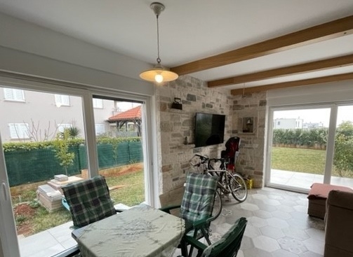 Stanza luminosa con travi in legno e due porte della terrazza