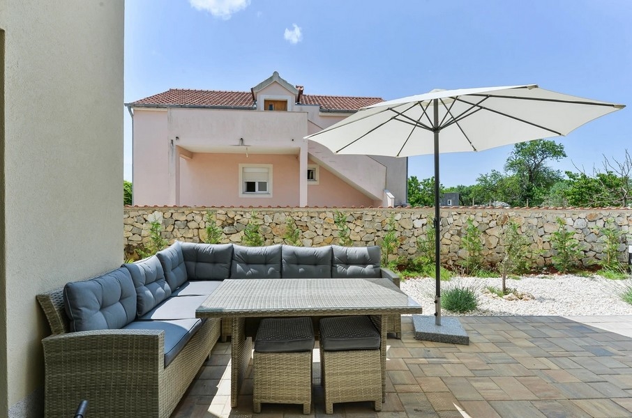 Lounge con tavolo da pranzo e ombrellone davanti al muro in pietra naturale