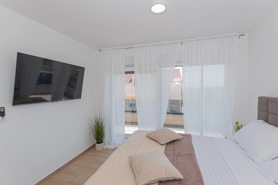 Camera da letto con televisore e tende alla porta del balcone