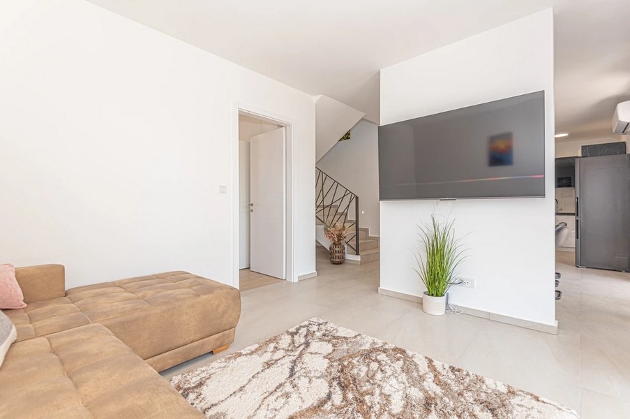 Zona giorno con divano beige e scala sullo sfondo