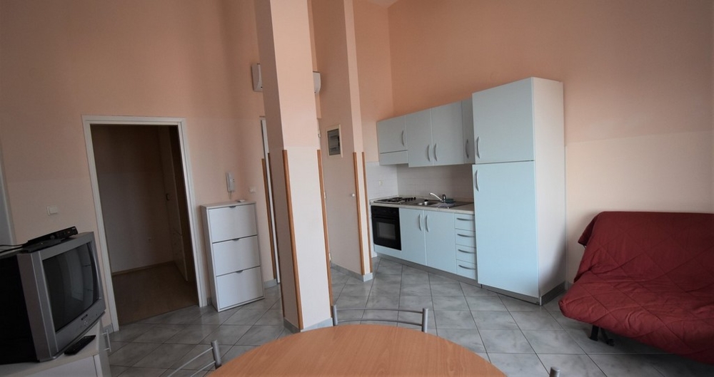 Cucina lineare azzurra con divano letto rosso accanto